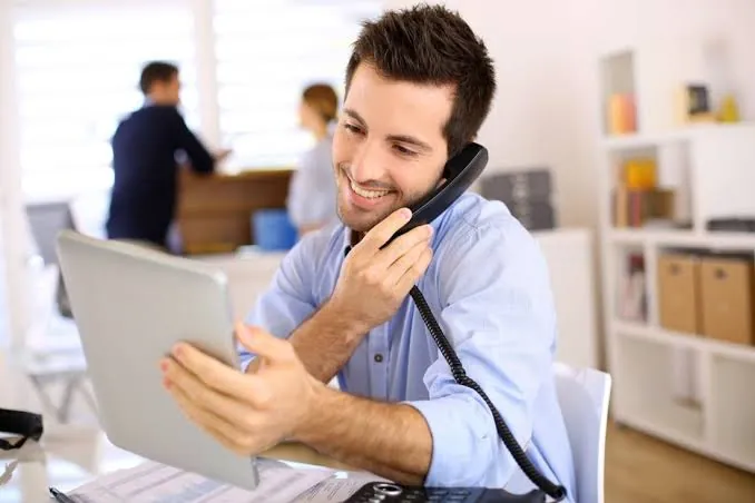 Personne souriante répondant au téléphone avec une tablette